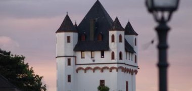 Burgturm der Kurfürstlichen Burg in der Dämmerung, rechts sieht man eine Straßenlaterne.